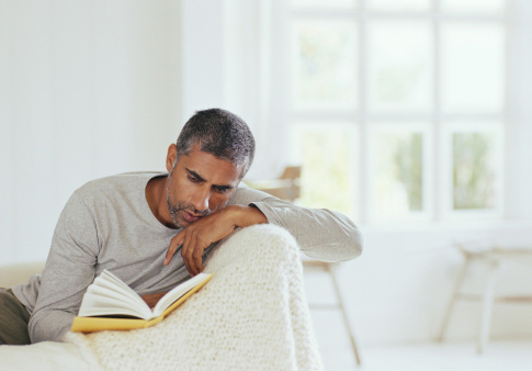 Man Reading On Sofa At Home