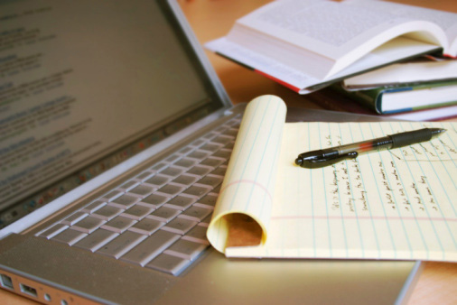 Pen and paper, books, and a laptop