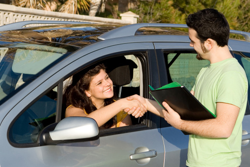 A man shaking the hand of a woman in a car